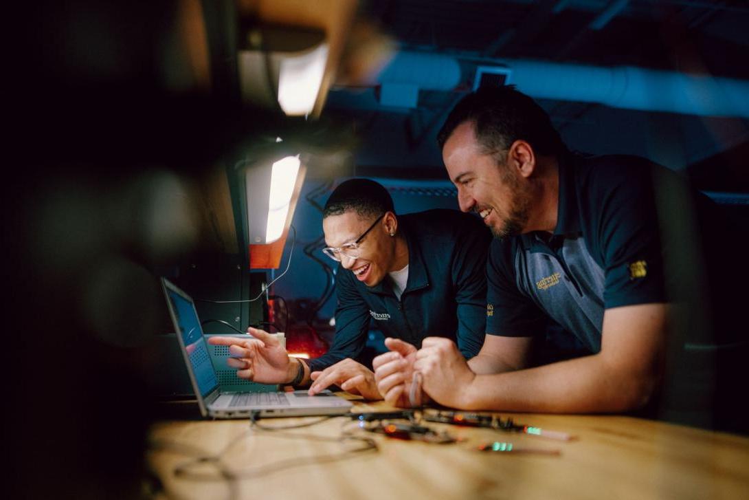 Two Kettering engineering students view the results of an experiment on a laptop screen. They're both smiling