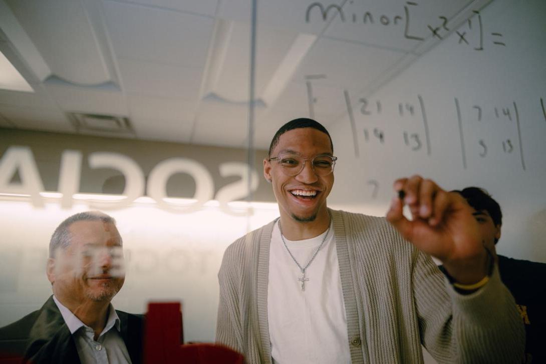 Kettering management student matrix equations on a glass wall. Another student and a professor watch